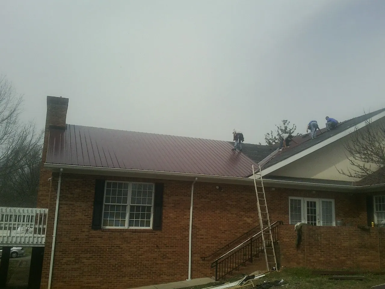 Crew setting red metal roofing panels on a brick home in Manitou Springs