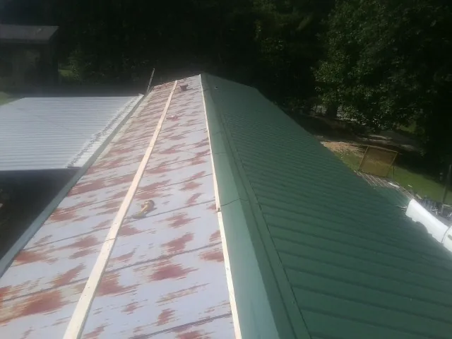 Old rusted panels beside newly installed green metal roofing — Wind Damage Roof Repair by Roofing Brothers in Manitou Springs