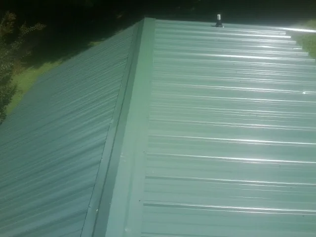 New green metal panels meeting at the ridge of a roof — Flat Roof Repair work by our crew in Manitou Springs