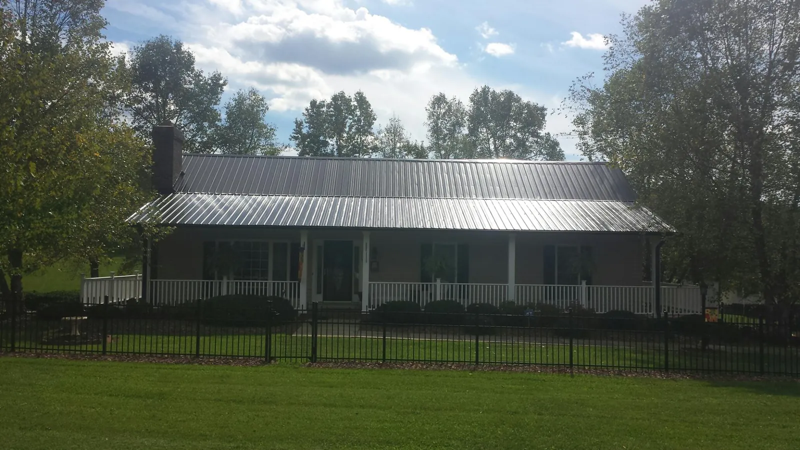 Gray metal roof on a brick ranch with a full width front porch — Gutter Guard Installation work by our crew in Manitou Springs
