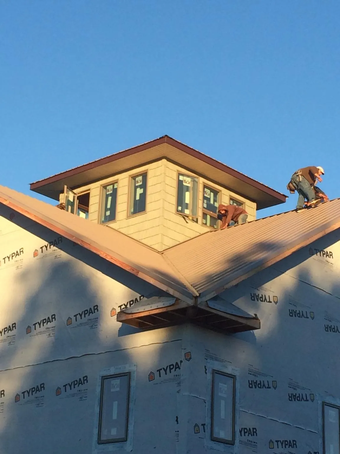 Roofers working around a rooftop cupola on a new metal roof at sunset — Roof Waterproofing in Manitou Springs by Roofing Brothers